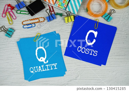 QC - Quality Costs text on stick note with stationery on concrete background 130415285