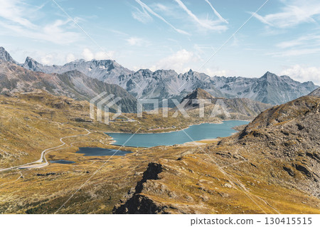 Breathtaking views of Lago Bianco reservoir at the Bernina Pass in Graubunden. Towering mountains and glaciers create a stunning alpine landscape under a clear sky. 130415515