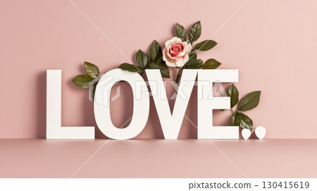 Large white wooden letters spelling love decorated with a delicate pink rose and green leaves on a pink background create a romantic atmosphere perfect for valentine's day or spring celebrations 130415619