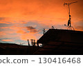 A vibrant orange sunset sky and the silhouette of a house 130416468