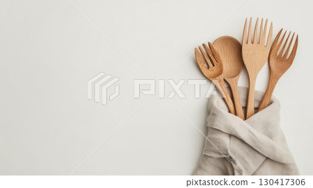 Wooden forks and spoons wrapped in natural fabric embody sustainable living and eco conscious choices for a greener future, minimizing plastic waste and embracing reusable alternatives 130417306