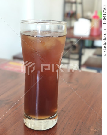 Refreshing iced tea with a full glass of ice on a wooden table. A perfect cool beverage to quench your thirst on a hot summer day. 130417502