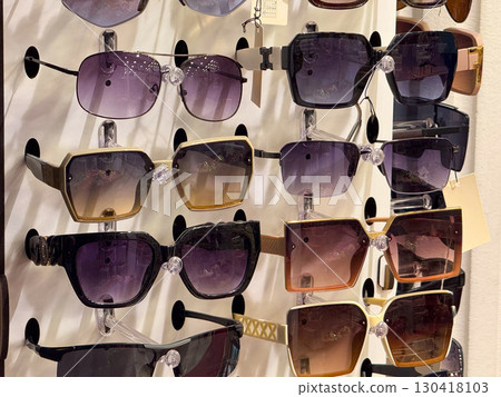 Various sunglasses with colorful lenses and frames displayed for sale in store. Fashion, protection and lifestyle emphasizing accessory, retail, and consumer choice in modern market. 130418103