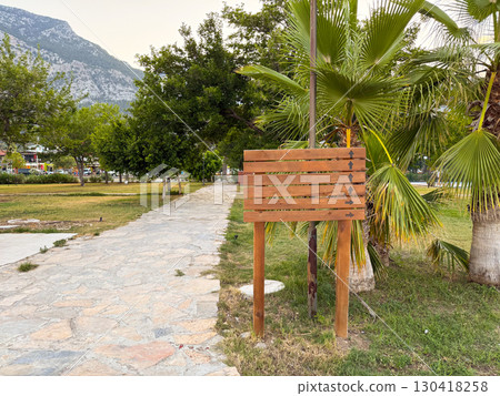 Wooden sign with multiple arrows provides direction in park environment. Travel, orientation, and navigation symbolizing guidance, tourism, and outdoor movement in natural landscape. Wooden sign with multiple arrows provides direction in park environment. Travel, orientation, and navigation symbolizing guidance, tourism, and outdoor movement in natural landscape. 130418258