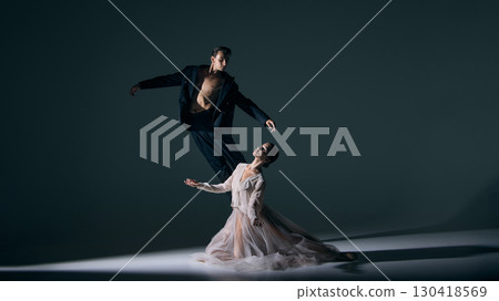 Male dancer leaping dynamically above female partner posed with elegance 130418569