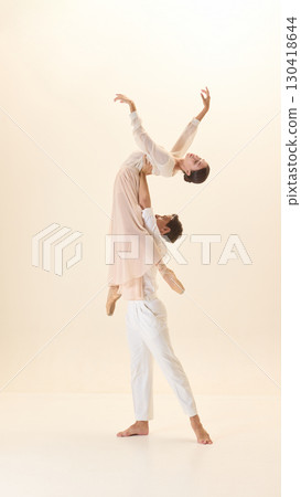 Ballet partners in white performing expressive lift in harmony 130418644