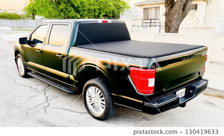 Sleek dark-green pickup truck with a tonneau cover parked on a residential street Sleek dark-green pickup truck with a tonneau cover parked on a residential street 130419633