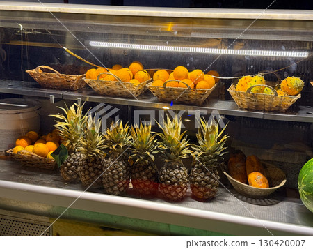 Fresh oranges and pineapples arranged in baskets inside market display. Healthy lifestyle, nutrition, and tropical fruit variety symbolizing freshness and natural flavor. 130420007