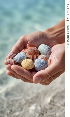 Woman holding colorful seashells in her hands, with a turquoise water background and blurred sandy beach in the foreground, evokes a sense of summer vacation and beachcombing Woman holding colorful seashells in her hands, with a turquoise water background and blurred sandy beach in the foreground, evokes a sense of summer vacation and beachcombing 130420374