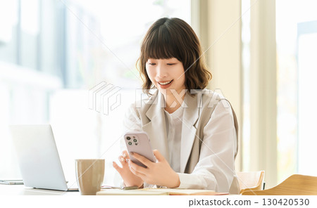 Smiling woman/businesswoman using a smartphone 130420530