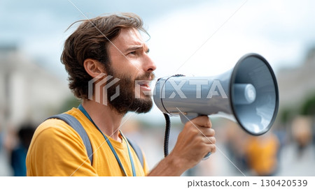 Young man with megaphone participating in a protest against immigration raids and ice policies, raising his voice for human rights and social justice in the united states 130420539