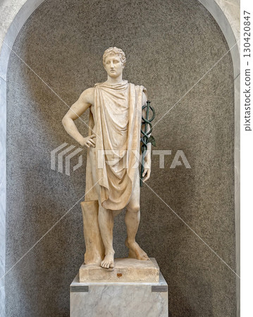 VATICAN CITY, ROME, ITALY - AUGUST 02, 2025 A classical marble statue of Hermes, known as the psychopomp holding a caduceus standing gracefully within an arched niche in the Chiaramonti Museum VATICAN CITY, ROME, ITALY - AUGUST 02, 2025 A classical marble statue of Hermes, known as the psychopomp holding a caduceus standing gracefully within an arched niche in the Chiaramonti Museum 130420847