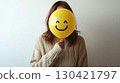 Woman Hiding Face with Smiley Balloon for Playful Expression 130421797