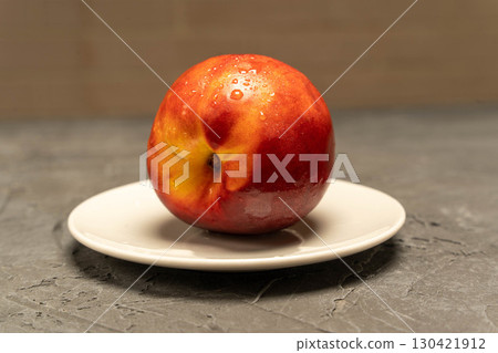 Ripe red peach in white saucer on grey background, fresh summer fruit Ripe red peach in white saucer on grey background, fresh summer fruit 130421912