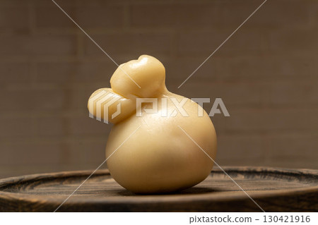 Goat cheese head in tied cloth bag on wooden board, artisanal farm product 130421916