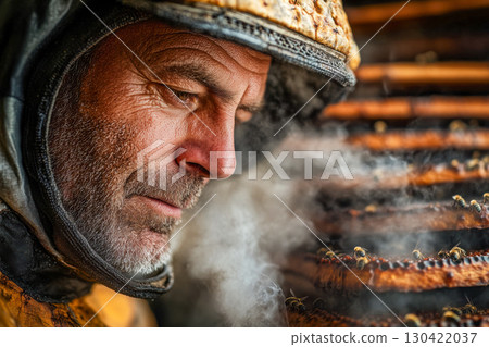 Close up of a focused beekeeper in protective gear carefully inspecting smoking honey frames teeming with active bees in a sunny apiary. 130422037