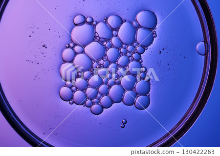 Serum with bubbles in a petri dish on a purple background. 130422263