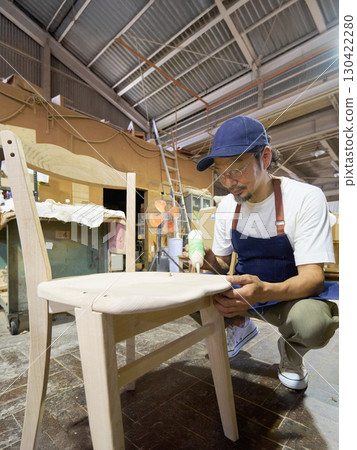 A craftsman gluing pieces together during the furniture assembly process 130422280