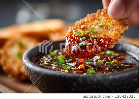 Hand dipping flavorful chamoy pickle slice into spicy sauce bowl Hand dipping flavorful chamoy pickle slice into spicy sauce bowl 130422325
