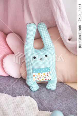 Soft blue checkered bunny toy in cozy pastel nursery setting with pillows Soft blue checkered bunny toy in cozy pastel nursery setting with pillows 130422771
