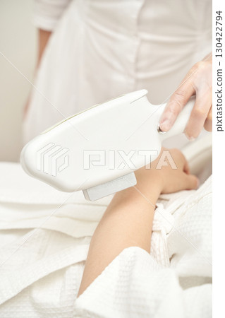 Female patient undergoing arm laser hair removal treatment in white medical Female patient undergoing arm laser hair removal treatment in white medical 130422794