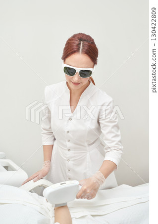 Female caucasian adult performing laser hair removal in clinical setting 130422809