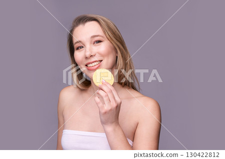 Young caucasian female smiling with cosmetic sponge in hand on purple background Young caucasian female smiling with cosmetic sponge in hand on purple background 130422812