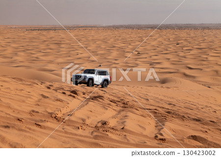 White SUV driving through desert sand, Saudi Arabia White SUV driving through desert sand, Saudi Arabia 130423002