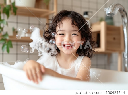 A cheerful toddler girl enjoys a bubbly bath, splashing in suds and smiling happily 130423244