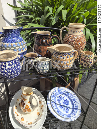 Colorful pottery collection displayed under sunlight in a cozy garden setting 130423572