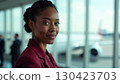 African-American flight attendant in red uniform with airport background, clear space for text. Perfect for airline brochures, websites, or training manuals 130423703