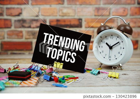 Trending Topics text on paper card with alarm clock and stationary on wooden background Trending Topics text on paper card with alarm clock and stationary on wooden background 130423896