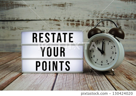Restate Your Points text on light box with alarm clock on wooden background 130424020