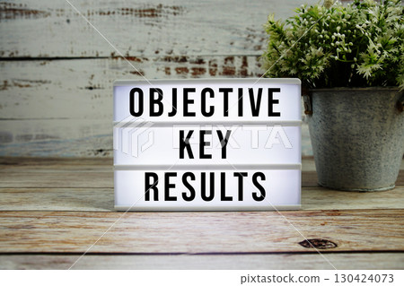 Objective Key Results text on light box with alarm clock on wooden background 130424073