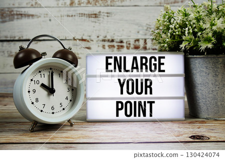 Enlarge your point text on light box with alarm clock on wooden background 130424074