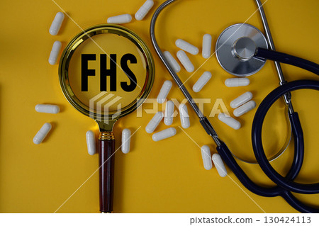 FHS abbreviation of Family Health Survey text on paper card with Stethoscope and magnifying glass flat lay on yellow background 130424113