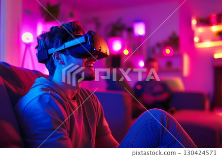 Young man wearing VR headset in colorful neon-lit room, experiencing immersive technology 130424571