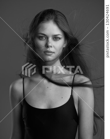 Black and white portrait of a young woman with long hair and serious expression wearing a black top. Black and white portrait of a young woman with long hair and serious expression wearing a black top. 130424691