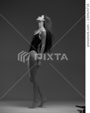 Black and white elegant woman in bodysuit posing with upward gaze in studio setting with minimalistic background. Black and white elegant woman in bodysuit posing with upward gaze in studio setting with minimalistic background. 130424716