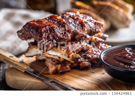 Pork BBQ glazed ribs and sauce on wooden cutting board. 130424961