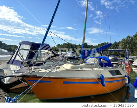 Boats parked by the lakeshore near wooden bridge in the early morning light. Calm water, reflection of forest and misty landscape. Peaceful nature scene, outdoor recreation, quiet lake atmosphere 130425150