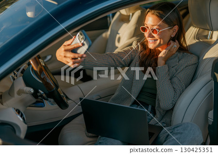 A Woman Enjoying a Virtual Meeting in a Very Stylish Car While Bridging Connections Effectively 130425351