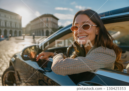 Joyful Young Woman Delightedly Enjoying a Scenic Drive Through the Beautiful City Streets 130425353