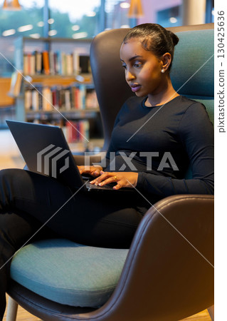 Focused student using laptop at library Focused student using laptop at library 130425636