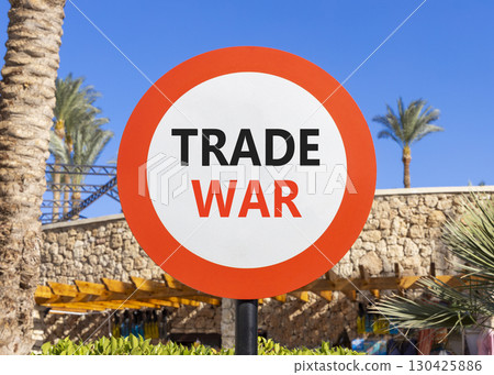 Trade war symbol. Concept word Trade war on beautiful red and white road sign. Beautiful palm tree and market blue sky background. Business trade war concept. Copy space. Trade war symbol. Concept word Trade war on beautiful red and white road sign. Beautiful palm tree and market blue sky background. Business trade war concept. Copy space. 130425886