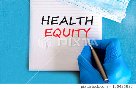 Health equity symbol. Concept words Health equity on beautiful white note. Doctor's hand in blue medical glove. Medical mask. Beautiful blue background. Medical healthy lifestyle health equity concept 130425983