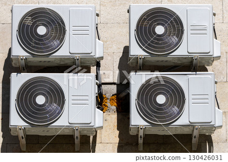 Four air conditioners are mounted on the wall. air conditioners are white. 130426031