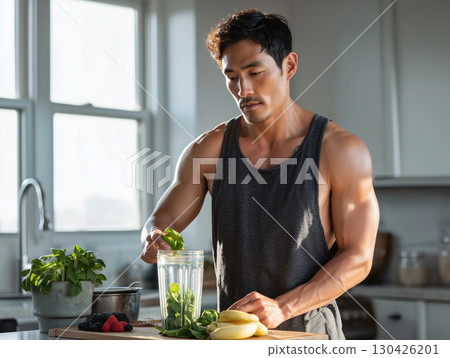 Fit man preparing healthy spinach and berry smoothie in kitchen with natural morning light and clean diet ingredients 130426201