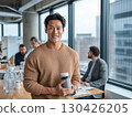 Smiling young man holding vitamin bottle in modern office promoting healthy habits and wellness lifestyle 130426205