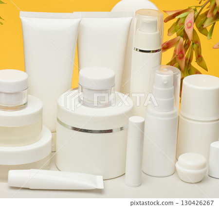 Set of white plastic cosmetic packaging without brand on yellow background. Container for beauty industry, skin care and advertising Set of white plastic cosmetic packaging without brand on yellow background. Container for beauty industry, skin care and advertising 130426267
